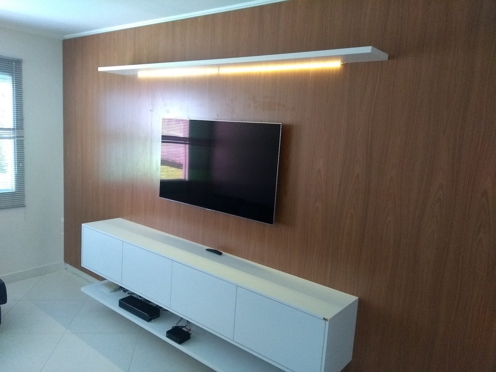 Painel de TV planejado em madeira com prateleira iluminada